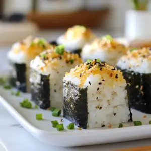 - 2 cups sushi rice - 2 ½ cups water - 1 cup cooked chicken breast, shredded - 1 teaspoon salt - 4 sheets of nori, cut into strips You need sushi rice for its stickiness. This helps the onigiri hold its shape. The water is essential for cooking the rice to fluffy perfection. Shredded chicken adds protein and flavor. The salt helps enhance the taste of all the ingredients. - 2 tablespoons soy sauce - 1 tablespoon sesame oil - 1 tablespoon mirin (optional) - 1 tablespoon furikake - 1 green onion, finely chopped Soy sauce adds a savory kick. Sesame oil brings a nutty flavor. Mirin is sweet and can enhance your dish if you choose to use it. Furikake adds a delicious finish, while green onion offers a fresh bite. - Rice cooker or pot - Mixing bowl - Measuring cups - Plastic wrap (optional) - Sharp knife for cutting nori Using a rice cooker makes cooking easier. A mixing bowl is perfect for blending your chicken and seasonings. Measuring cups ensure you get the right amounts. Plastic wrap can help shape your onigiri. A sharp knife will help cut the nori cleanly. {{ingredient_image_1}} Start by rinsing the sushi rice. Use cold water until it runs clear. This step removes extra starch. Then, cook the rice with 2 ½ cups of water. You can use a rice cooker or a pot. Follow the package instructions until the rice is fluffy. Once cooked, let it cool for a short time. In a medium bowl, mix the shredded chicken with soy sauce, sesame oil, and salt. If you have mirin, add it too. This mix adds flavor to the chicken. Set the mixture aside to marinate for about ten minutes. This allows the flavors to blend well. Now, dampen your hands with water. This prevents the rice from sticking. Take about 1/3 cup of rice and make a small dent in the center. Add a spoonful of the chicken mix into the dent. Gently mold the rice around the filling. Shape it into a triangle by pressing the rice together. Repeat this until you use all the rice and filling. Sprinkle some furikake on top for extra taste. Wrap a strip of nori around the bottom of each onigiri. This makes it easy to hold. Lastly, add a sprinkle of chopped green onion for a fresh touch. To stop sushi rice from sticking, rinse it well. Use cold water until the water runs clear. This step removes excess starch. After cooking, let the rice cool a bit. Dampen your hands with water before handling the rice. This helps keep it from sticking to your fingers. For the best onigiri shape, take about 1/3 cup of rice. Use your fingers to make a small dent in the center. Add a spoonful of the marinated chicken in the dent. Gently mold the rice around the filling. Press it firmly but not too hard. A triangle shape is classic for onigiri. Repeat until you finish the rice and chicken. When serving, arrange the onigiri on a bright plate. Add some extra nori strips for a nice look. You can also sprinkle sesame seeds for color. Serve with pickled ginger or soy sauce on the side. These add a tasty touch and enhance the meal. Enjoy your delightful and nutritious chicken onigiri! Pro Tips Rinse Thoroughly: Ensure you rinse the sushi rice well until the water runs clear to achieve that perfect fluffy texture. Marinating Time: Allow the chicken to marinate for at least 10 minutes to enhance the flavor, but don’t oversoak it. Shaping Tips: When shaping the onigiri, keep your hands slightly damp to prevent the rice from sticking and to help mold it easily. Serving Suggestions: For a beautiful presentation, serve the onigiri on a colorful plate with garnishes like sesame seeds or pickled ginger. {{image_2}} You can change the filling in onigiri to match your taste. Try using cooked salmon, tuna, or even pickled vegetables for a twist. You can also use avocado for a creamy texture. For a spicy kick, mix sriracha with your protein. The options are endless and fun to explore! While sushi rice is great, you can use other rice types too. Brown rice adds a nutty flavor and more fiber. Jasmine rice gives a fragrant aroma. Remember to adjust water levels based on the rice type you choose. Each rice type offers a unique taste and texture. To make gluten-free onigiri, choose gluten-free soy sauce. You can also swap out mirin for a rice vinegar or a gluten-free alternative. The fillings can be made with chicken, shrimp, or veggies. These options keep your onigiri tasty and safe for those avoiding gluten. Store onigiri in an airtight container. This keeps them fresh and moist. If you leave them out, they can dry out. You can also wrap them in plastic wrap. This method helps keep their shape and flavor. To freeze onigiri, wrap each piece in plastic wrap. Place them in a freezer bag. They stay good for up to three months. When you want to eat them, take out what you need. Let them thaw in the fridge overnight. This keeps the texture nice. Reheat onigiri in the microwave. Place them on a plate and cover with a damp paper towel. Heat for about 30 seconds. This keeps them from getting too dry. You can also pan-fry them for a crispy outside. Just heat a little oil in a pan and cook until warm. Onigiri is a popular Japanese snack. It often shows love and care in cooking. Families make these rice balls for picnics and special occasions. Onigiri also connects people through shared meals. The triangle shape symbolizes harmony in Japan. This comfort food is easy to carry and eat. It represents simple, wholesome cooking. Yes, you can use other proteins! Chicken is just one option. You can try tuna, shrimp, or tofu. These proteins can add different flavors. Just make sure to season them well. You can mix them with soy sauce or spices. This way, you can make your onigiri unique. To make vegan or vegetarian onigiri, swap the chicken for veggies. Cooked mushrooms or seasoned tofu work well. You can also use avocado for creaminess. Add spices and sauces for more flavor. This way, you can enjoy onigiri while keeping it plant-based. Remember to keep the rice and nori for that classic taste! In this post, I covered how to make chicken onigiri. We discussed the main ingredients, seasoning options, and helpful tools for preparation. I shared step-by-step instructions for rice prep, chicken filling, and shaping the onigiri. Tips included preventing sticking and proper serving. We explored delicious variations and best storage practices. Onigiri is fun to make and enjoy. With these ideas, you can create tasty meals or snacks. Dive into this delicious dish and let your creativity shine!